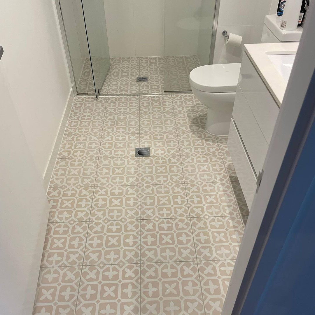 Bathroom with patterned floor tiles, glass shower screen and white vanity