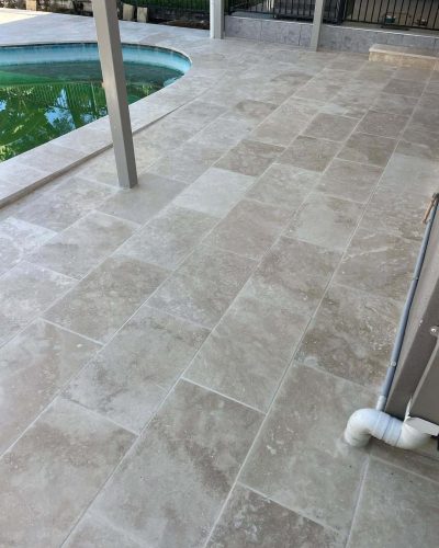 Pale stone pavers on a pool deck around a pergola post