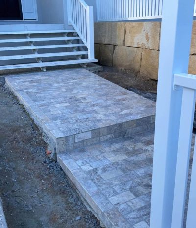 Grey stone-tiled landing and step at the foot of white stairs