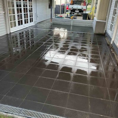 Glossy dark grey tiles on a wide verandah beside white French doors