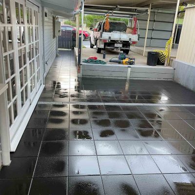 Dark grey verandah tiles with a work ute parked in the carport beyond