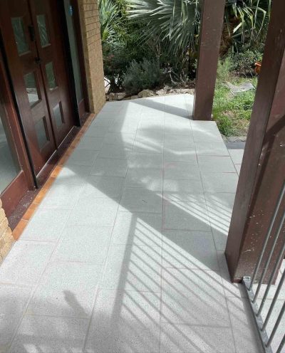 Light grey tiles along a covered walkway beside timber doors