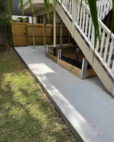 Concrete path along a lawn beside white timber stairs