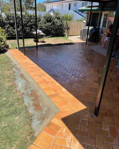 Red herringbone brick pavers along a patio edge, freshly laid beside a lawn