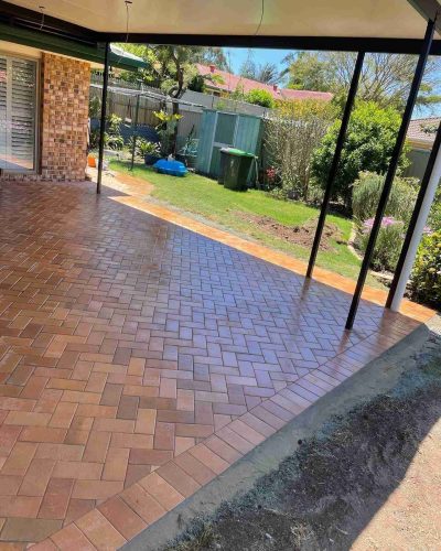 Herringbone brick-paved patio under a roof, looking out to the backyard