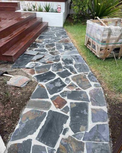 Crazy-pave stone path leading to timber deck steps beside a lawn