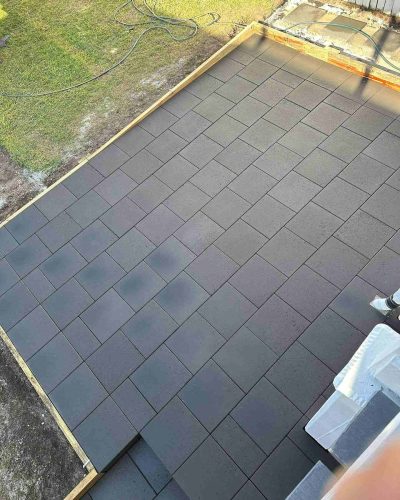 Dark grey pavers with timber edging, seen from above beside the lawn